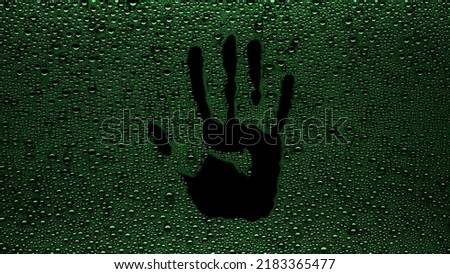 Handprint printed on the wet glass with green drops on black background | shower concept