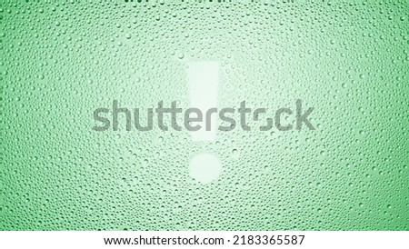 Exclamation sign printed on the wet glass on green background | warning concept