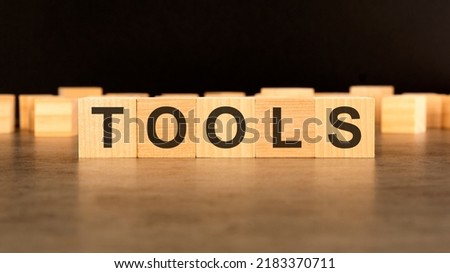 word TOOLS is written on wooden cubes standing on black background
