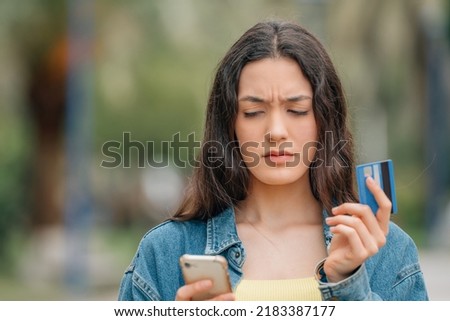 girl with mobile phone and credit card with expression of doubt or mistrust Royalty-Free Stock Photo #2183387177