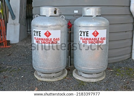 Two large gas cylinders in front of a plastic water tank