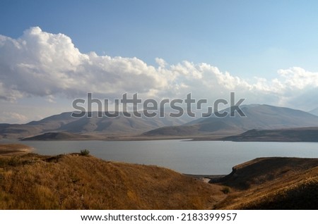 The rays of the sun are reflected in the water of a picturesque reservoir surrounded by mountains. Natural landscapes of Armenia
