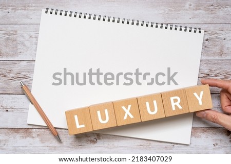 Wooden blocks with "LUXURY" text of concept, a pen, and a notebook.