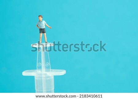 Miniature people toy figure photography. Vaccination for kids concept. A kid boy standing above syringe invites to get vaccinated. Image photo
