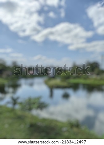 defocused abstract background of a lake with calm water and a statue in the middle decorated with a cloudy blue sky