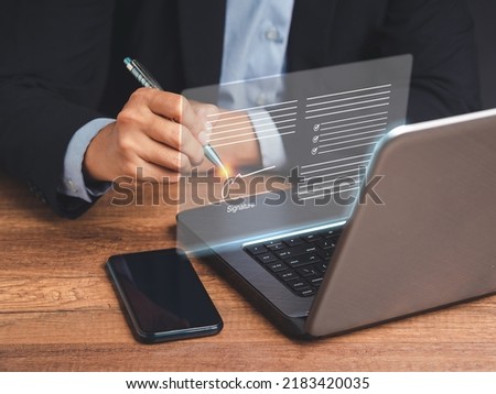 Electronic signature. A businessman in a suit uses a pen to sign electronic documents on digital documents on a virtual screen. Technology, document management, and paperless office concept Royalty-Free Stock Photo #2183420035