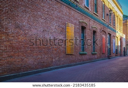 Urban Alley in old city. Old grunge street. Grungy urban background of a brick wall with windows. Travel photo, nobody, copy space for text Royalty-Free Stock Photo #2183435185