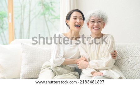 Asian elderly woman and middle aged woman smiling in the room. Royalty-Free Stock Photo #2183481697