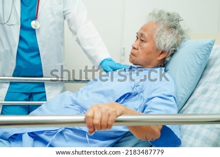 Asian elder senior woman patient holding bed rail while lie down with hope waiting her family in hospital.