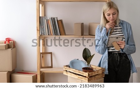 Unhappy woman enjoying while looking at a photo after moving into her new home. unboxing package at new house