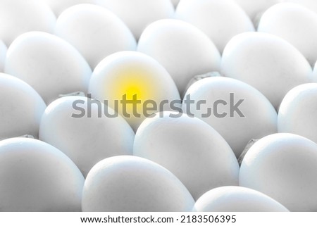 Yellow light in one egg among many white eggs.Special, stands out from others. Individuality.