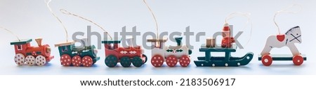 Christmas tree toys, colored wooden locomotives and Santa with gifts on a sleigh, wooden horse. Blue background, horizontal banner for design.