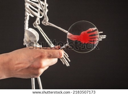 Hand with magnifying glass over carpal bones of human skeleton with red spot. Wrist pain. Arm sprain, fracture. Anatomy study, medicine concept. High quality photo