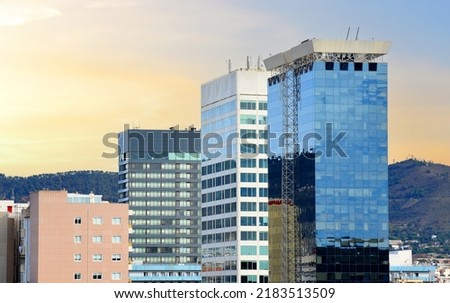 Skyscraper building facade. Skyscrapers office buildings in Barcelona. Glass facade with windows. Urban architecture on sunset at mountains. Wall made of toned glass and steel construction.  Royalty-Free Stock Photo #2183513509