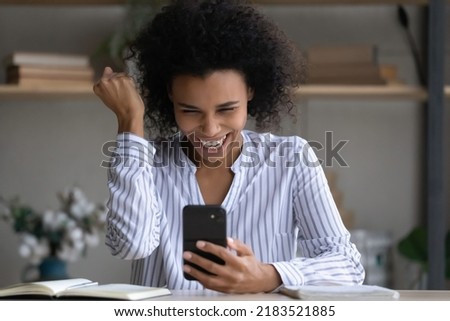 Head shot overjoyed African American woman celebrating success, showing yes gesture, looking at smartphone screen, happy young female reading good news, received job promotion or lottery win Royalty-Free Stock Photo #2183521885