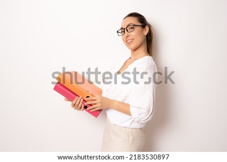Cheerful young business woman in white shirt posing isolated on white background studio portrait. Achievement career wealth business concept. Mock up copy space. Holding folders for papers document