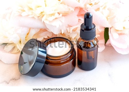 anti-aging collagen facial serum in dark glass bottle and face cream on white background with copy space. Natural Organic Cosmetic Beauty Concept. Mockup for branding.