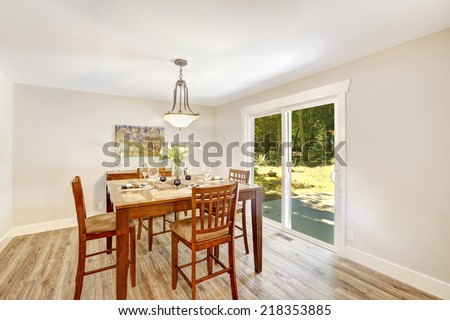 Bright ivory dining room with walkout patio. Wooden dining table with chairs
