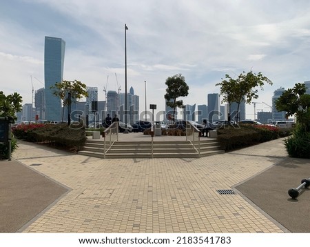 A city park pictured in Dubai's Business Bay, with parked cars in the foreground and the city skyline in the background