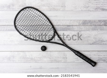 Black squash racket and ball on grey court. Horizontal sport theme poster, greeting cards, headers, website and app Royalty-Free Stock Photo #2183541941