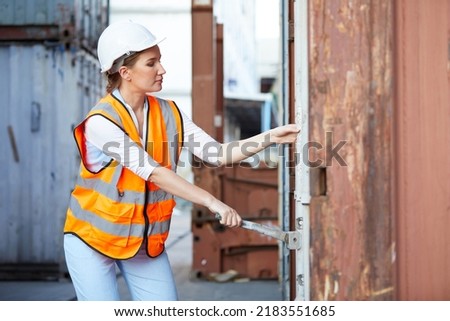 young female factory worker or engineer opening the container door in warehouse storage