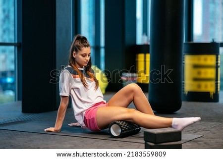Young woman using a foam roller while doing stretching exercises Royalty-Free Stock Photo #2183559809