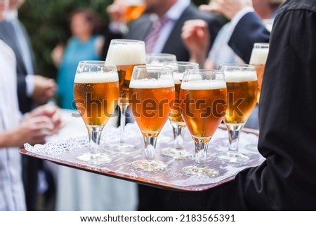 Waiter serving several beers in glasses on a tray to guests at an event, wedding, party, etc. Royalty-Free Stock Photo #2183565391