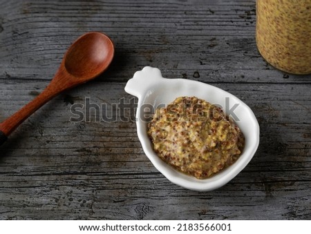 Old mustard on a white plate in rustic background