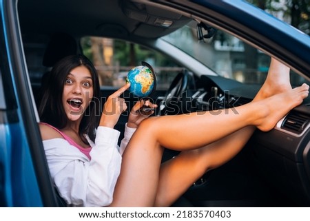 Young woman sitting in a car and holding a globe