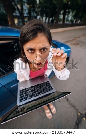 Shocked young brunette hold in hands laptop on the street