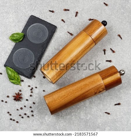 Closeup photo of salt and pepper mills lying on gray background.