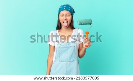 pretty hispanic woman with cheerful and rebellious attitude, joking and sticking tongue out. painting home concept
