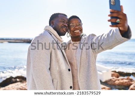 Man and woman couple standing together make selfie by the smartphone at seaside