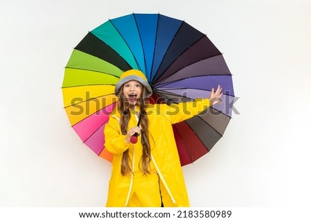 A child with an umbrella and in a yellow raincoat and panama hats. Beautiful little girl with long hair on a white isolated background.