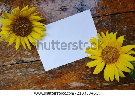 Greeting card mockup on wooden background with sunflowers.