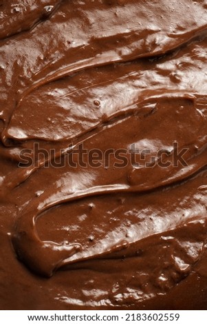 a close-up on chocolate ganache or pudding with swirls and spreads filling the frame, selective focus