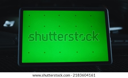 Modern gadget digital tablet computer with green screen chromakey on the hood of a black car during diagnostics in a car service