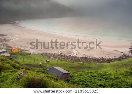 Beautiful Keem beach before sun rise. Fog over the ocean surface. Calm and peaceful mood. Irish landscape and popular travel area with water sport and hiking and amazing scenery. County Mayo, Ireland