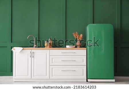 Kitchen counter with sink and retro fridge near green wall