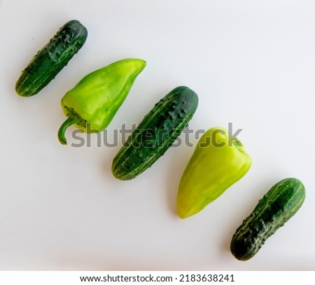 Ripe fresh green cucumber and bell pepper, laid out in a row, is highlighted on a white background. A young summer harvest, vitamins and proper healthy nutrition.Selective focuse