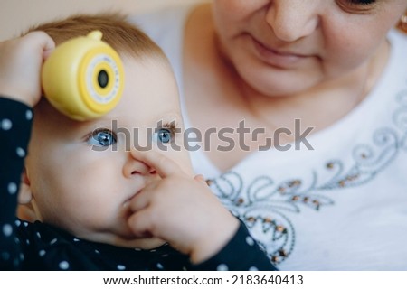 little caucasian baby girl and grandmother. woman hugging granddaugher with love. Image with selective focus and noise effect