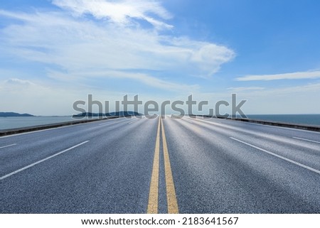 Straight asphalt road and river with mountain nature landscape under blue sky Royalty-Free Stock Photo #2183641567