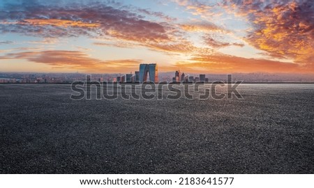 Asphalt road and city skyline with modern commercial building at sunset in Suzhou, China. 
