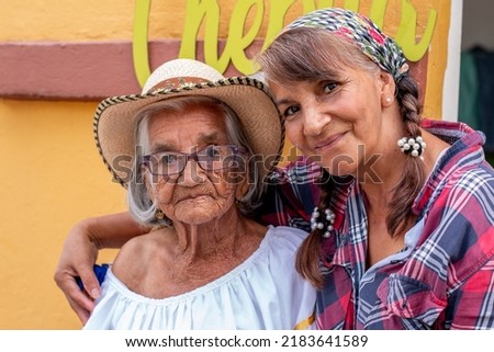 Portrait of old peasant woman with her smiling daughter wearing typical Colombian clothes. Women with brown skin. Royalty-Free Stock Photo #2183641589