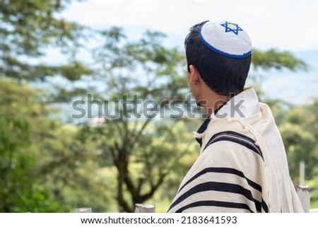 Jewish man looking at a landscape dressed in tallit and kippah seen from the back. Royalty-Free Stock Photo #2183641593