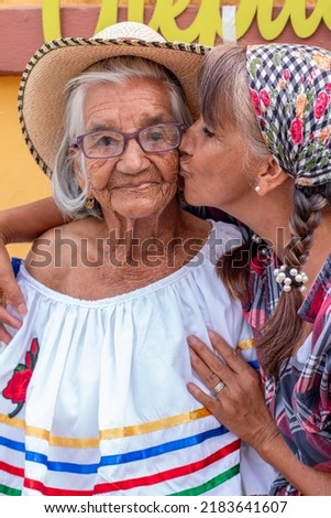 Woman gives a tender kiss on the cheek to her 95 year old mother. Portrait of mother and daughter.
