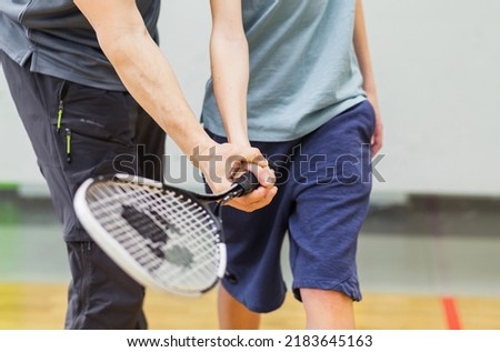 Male coach  teaches a child how to hold a tennis racket. Horizontal photo Royalty-Free Stock Photo #2183645163