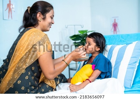Mother feeding porridge to ill kid while admitted at hospital ward - concept of parental caring, medical treatment and health care. Royalty-Free Stock Photo #2183656097