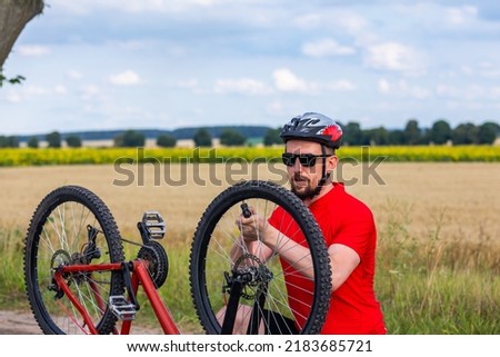 bike repair. young man repairing red mountain bike in the field