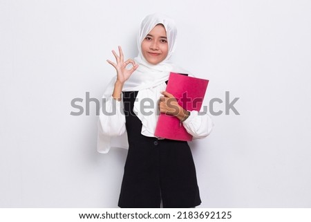 beautiful asian business muslim woman hug a book fist and tumb up ok isolated on white background
